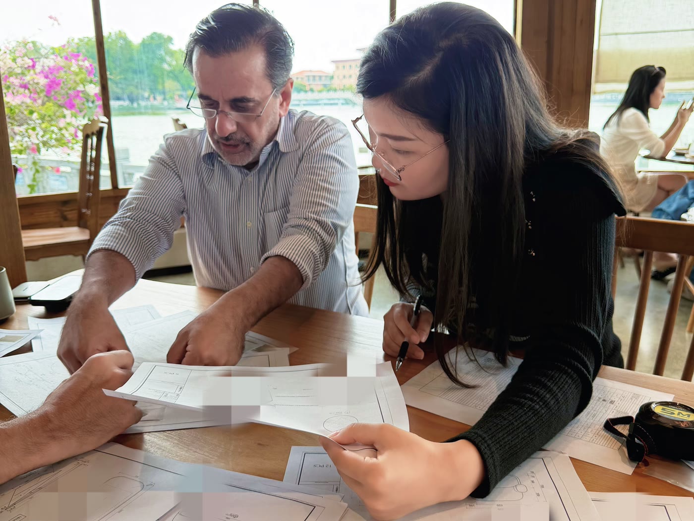 A buyer reviews CAD production drawings over real wood samples at the TY factory